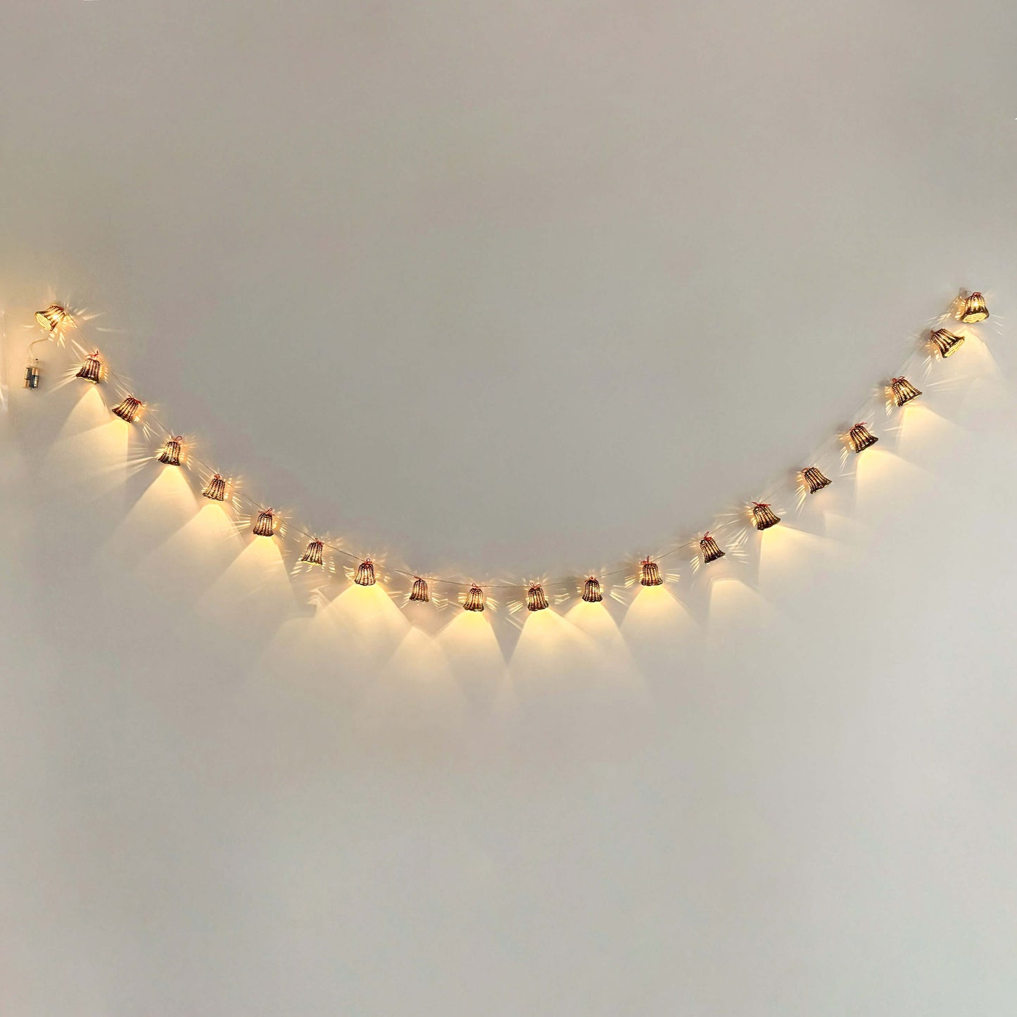 20 adet el yapımı rattan çan başlıklı LED ışık zinciri, kırmızı ip detaylı, beyaz zeminde dağınık konumda – pille çalışan dekoratif boho aydınlatma