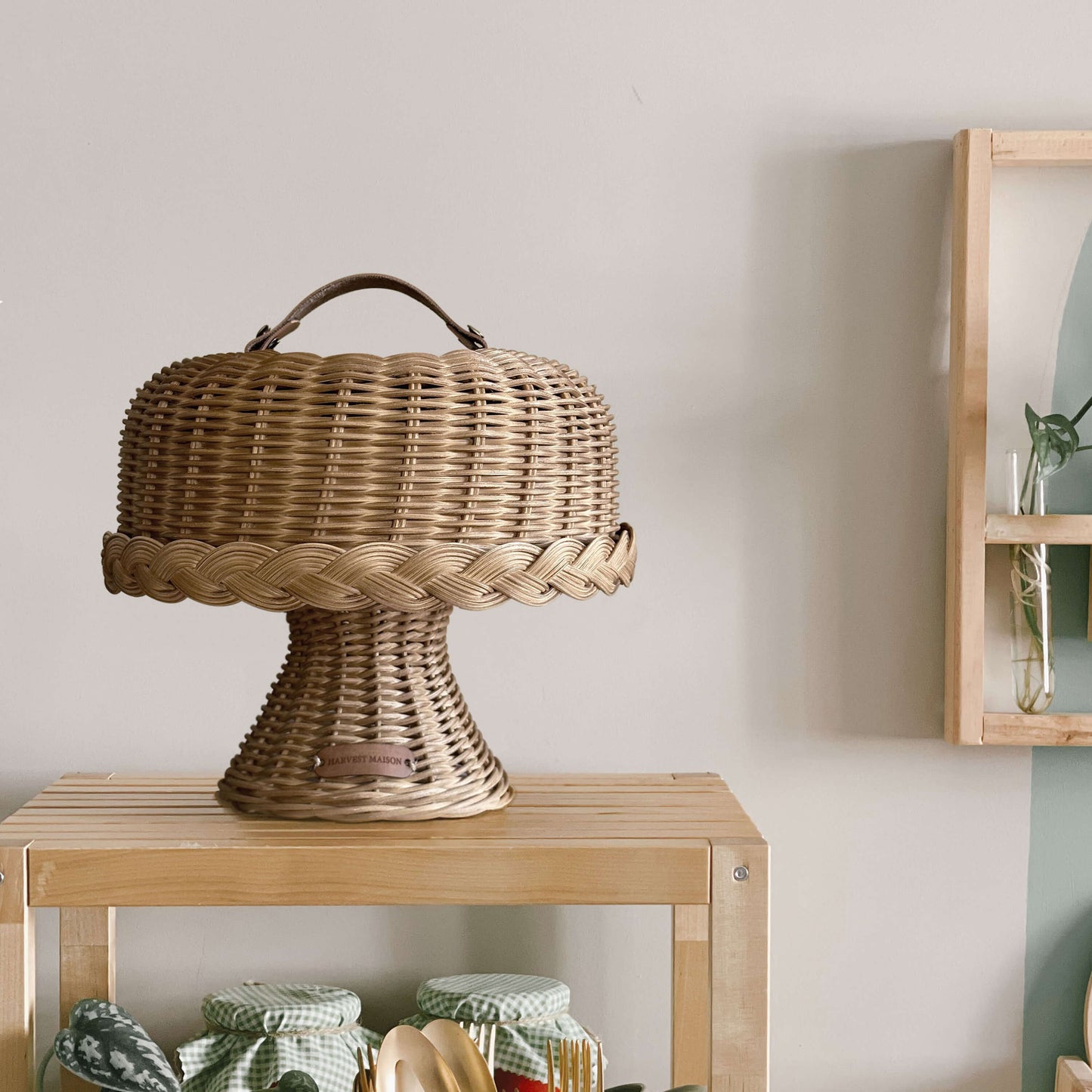 Boho tarzında dekore edilmiş bir mutfakta, el yapımı hasır ve rattan malzemeden üretilmiş kapaklı ayaklı kek ve pasta standı fanusu; doğal detaylarla şık bir şekilde sunuluyor