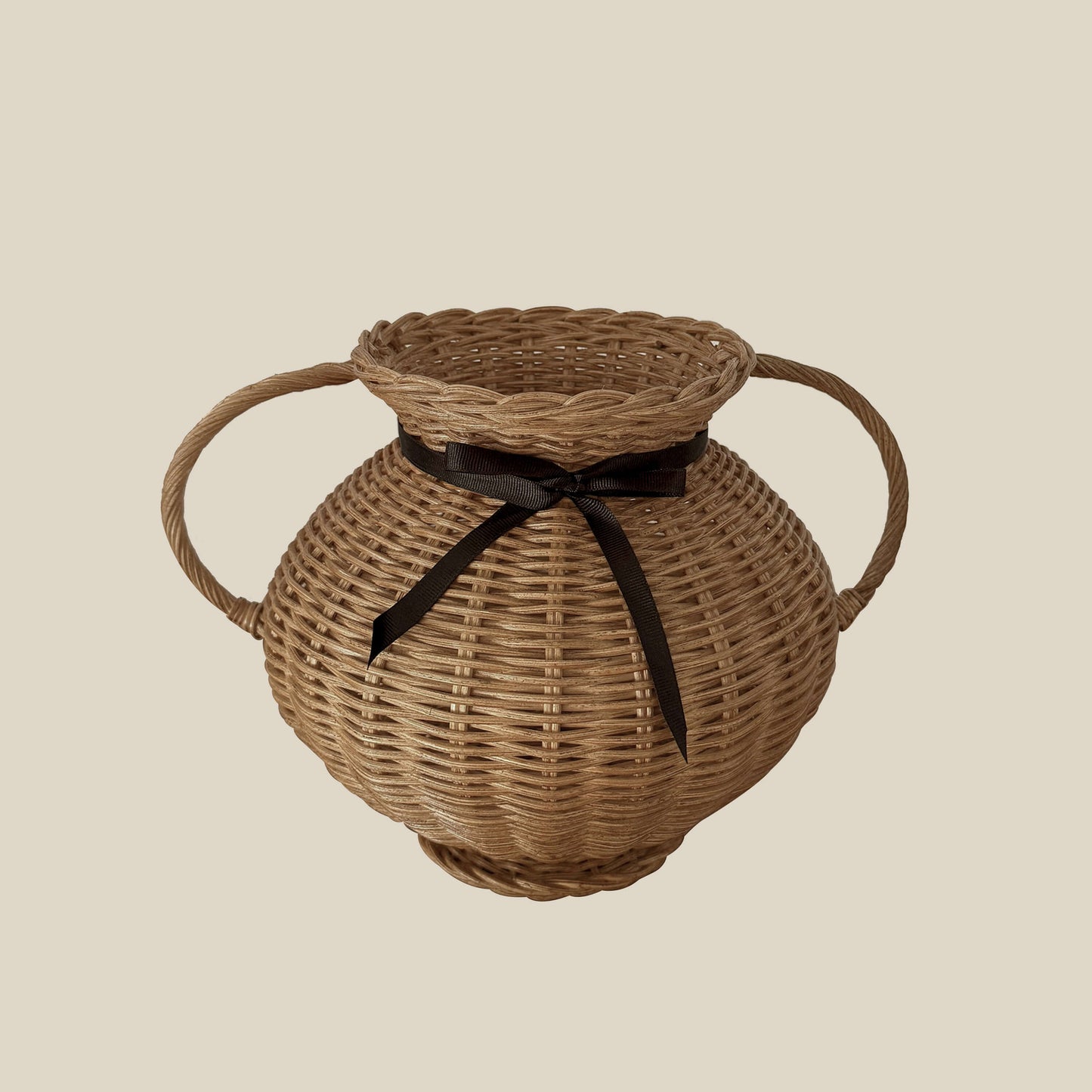Kulplu el yapımı rattan vazo, siyah kurdele ile bağlanmış, yayvan formlu. Modern ahşap yemek masası üzerinde, kuru otlarla dekore edilmiş
