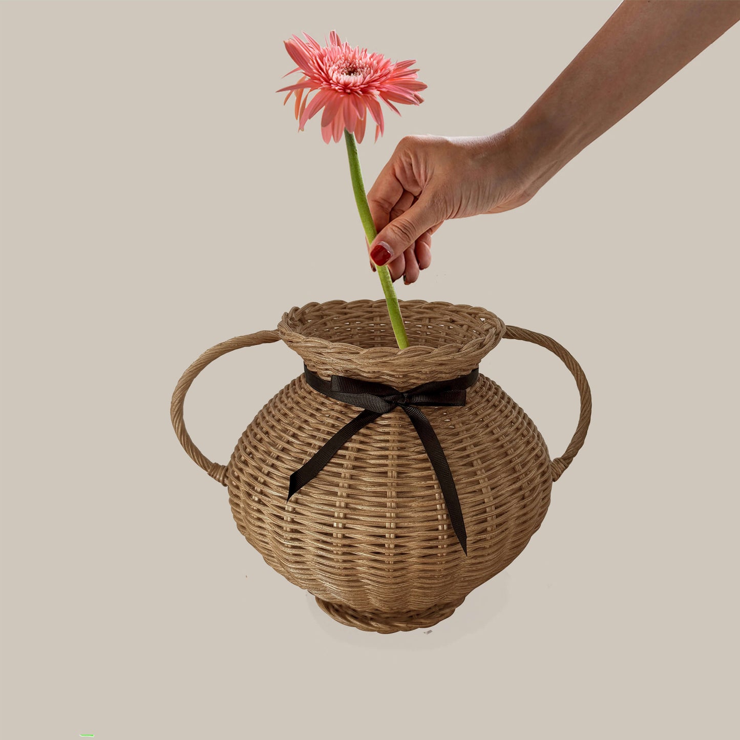 Kulplu el yapımı rattan vazo, siyah kurdele ile bağlanmış, yayvan formlu. Modern ahşap yemek masası üzerinde, kuru otlarla dekore edilmiş
